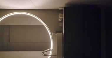 Çağdaş minimalist banyo dairesel LED arka ışıklandırma aynası ve parlak lavabo modern ve sakin bir atmosfer yaratıyor. Dairesel LED Arka Işıklı Dikey Aynalı Modern Minimalist Banyo