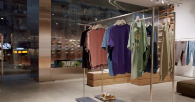 Moda bir giyim mağazasında çeşitli gömlekler, ayakkabılar ve kaykaylar sergileniyor. Genç, modaya uygun müşterilere hizmet veren mağaza, modern sokak kıyafetlerini bir parça paten kültürü ile somutlaştırıyor.,