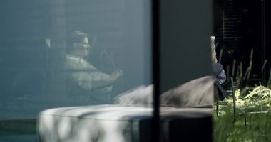 Huzurlu bir ortamda yansıtıcı camdan görülen bir adam ve bir kadın. Yansıma ve samimiyet anı yakalandı. Modern Evde Düşünceli Çift, Yansıtıcı Cam Görünümü