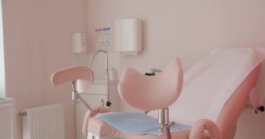 Temiz ve modern bir jinekolog ofisi. Yumuşak pembe bir duvara dayalı pembe bir muayene koltuğu var. Klinik rahatlık ve nazik bir estetik. Modern Jinekolog Ofisi Ekipmanı