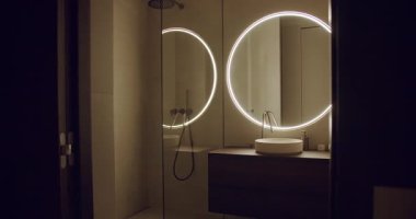 Arka planda aynalar, gösterişli gösteriş, minimalist eşyalar ve ortam aydınlatması olan çağdaş bir banyo. Tasarım zarafet, sofistike ve sakin bir atmosfer yayar. Modern Banyo