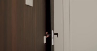 Ahşap kapıyı açan sıradan iş kıyafeti giymiş bir kadının yan görüntüsü. İç mekan. Ahşap kapıyı açan kadın. Kapalı alanda günlük iş kıyafeti giyiyor.