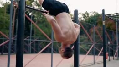 Kaslı adam yatay çubukta barfiks çekiyor. Kararlı bir atletin vücut gücü için beden eğitimi rutinini yavaş çekimde çekmesi. Fitness motivasyonu ve antrenman hedefleri.