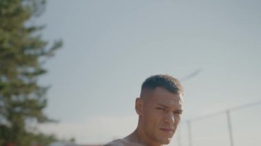 Dışarıda güneşin altında egzersiz yapan kaslı bir adamın arka görünüşü, dayanıklılık ve zindelik gösteriyor. Sıcak güneş ışığı atletik yapıyı ve açık hava ortamını vurguluyor. Atletik Adam Egzersizinin Arka Görünümü