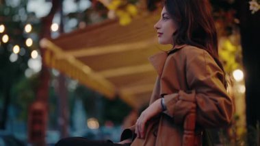 Dekoratif sicim lambaları ve bulanık arka planı olan, şehir gece hayatı titreşimlerini yakalayan açık havada ceketli genç bir kadının portresi. Şehirdeki Genç Kadın Açık Hava Ayarları