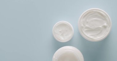 Stüdyoda açık mavi arka planda kozmetik ürünleri için beyaz şişe ve tüpler. Saç ve cilt bakımı için doğal kozmetik ürünleri. Kremalı parlak kozmetik kavanozu. Farklı kozmetik şişeleri grubu.