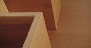 Ahşap mobilyaların ince işçiliğine odaklanan modern bir minimalist iç mekanın yakın plan görüntüsü. Görüntü, ahşabın dokusunu ve sıcak tonlarını güzel bir şekilde yakalıyor, tasarım estetiği. Dikey