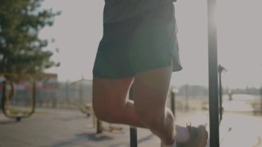 Formda bir adam güneş doğarken paralel barlarda egzersiz yapar. Gücü, zindeliği ve kararlılığı vurgular. Sağlık, sağlık ve egzersiz kavramları için mükemmel bir imaj. Erkek Egzersizi 