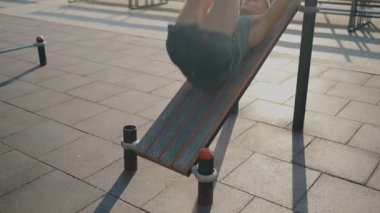 Açık havada spor yapan genç bir adam halka açık bir parkta spor yapıyor, gücü ve zindeliği vurguluyor. Sağlık, yaşam tarzı ve egzersiz kavramları için ideal. Genç adam dışarıda egzersiz yapıyor.