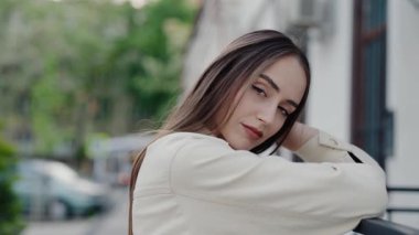 Genç bir kadın şehir merkezindeki korkuluklara dayanıyor, rahatlama ve sakinlik yayıyor. Yeşil bulanık arka plan sahnenin sükunetini arttırır. Açık havada Kadın Pozu