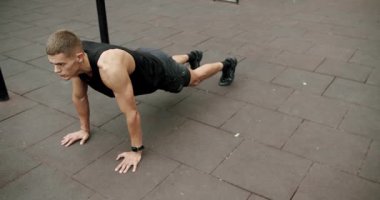 Atletik vücutlu bir adam sabah sporunu dışarıda yapar ve şınav çeker. Sportif adam spor sahasında kol kaslarını çalıştırıyor ve eğitiyor. Etkin yaşam tarzı kavramı.