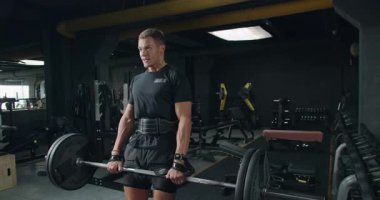 İyi donanımlı bir spor salonunda ağırlık antrenmanı sırasında halter kaldıran odaklı bir erkek sporcu. Kararlılığın ve gücün ifadesi. Spor salonunda Ağırlık Kaldıran Kararlı Adam, Spor Salonu