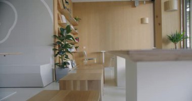 Zarif ve havalı modern ofis iç mimarisi doğal ahşap mobilyalar, kapalı ev bitkileri ve çağdaş tasarım unsurları sergiliyor. Fotoğraf, ahşap masalar, raflar ve rahatlatıcı, temiz bir estetik içeriyor..