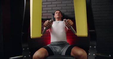 Spor salonunda göğüs pres makinesi kullanan odaklanmış bir sporcu. Arka planda modern ekipman ve motivasyon salonu atmosferi var. Genç Adam Spor Salonunda Göğüs Baskısı Makinesi Eğitimi