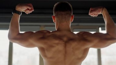 Genç bir adamın güçlü bir görüntüsü sırt kaslarını esnetiyor, bir spor salonundaki gücünü ve bağlılığını gösteriyor. Modern Jimnastik Ortamı 'nda Genç Erkek Sporcu Kaslarını Esnetiyor