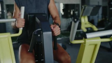 Spor makinesinde çalışan bir adamın yakın plan çekimi. Güç ve fitness antrenmanına odaklanıyor. Egzersiz, sağlık ve vücut geliştirme kavramları için ideal. Spor Salonundaki Güç Makinesinde İnsan Egzersizi