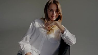 Beyaz bir gömlek giyen genç bir kadının portresi, eli çenesinde rahat poz veriyor, yumuşak doğal ışıkla aydınlatılıyor. Beyaz Gömlekli Genç Kadın Hafif Aydınlıkta Gelişigüzel poz veriyor