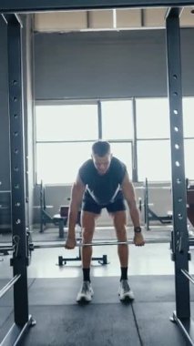 Modern bir spor salonunda halter kaldıran kaslı bir adam. Fitness, güç ve sağlıklı bir yaşam tarzına adanmışlık. Erkek Vücut Geliştirici Halter Yapıyor