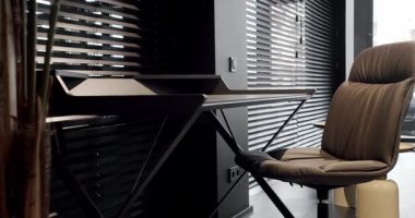 Rahat çalışma odasında minimalist deri koltuklu modern ahşap çalışma masası. Oda palmiyesi dekoru. Minimalist siyah panjurlar. Beauty Interior 'da yatak odası aksesuarı, deri koltuk ve modern masa..