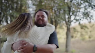 A tender moment captured as a couple in love embraces warmly under the tree canopy in a peaceful park setting. Loving Couple Embracing Under Trees in a Serene Park