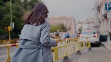 Şık bir saç stiline sahip modern genç bir kadın şehir ortamını keşfediyor. Etrafı hareketli şehir trafiği ve tuhaf binalarla çevrili olan akıllı telefonuna bakıyor..