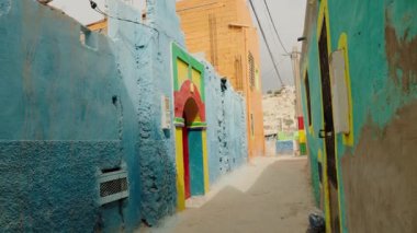 Fas 'ta renkli bir sokak. Duvarlar mavi, yeşil, turuncu ve sarı renkli canlı renklerle boyanmıştır. Fas mimarisinin ve kültürünün özünü yakalamak, seyahat için büyüleyici bir sahne...