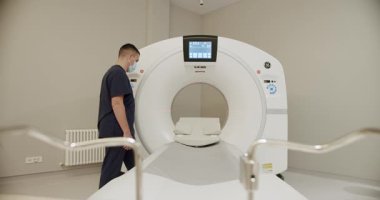 Olgun doktor teknik ekipmanları ayarlar. Modern CT makinesi klinikte. Modern hastanenin ışık laboratuarına kurulmuş modern CT makinesinin sol ve sağ görüntüsünü kaydır