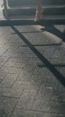 Beyaz elbiseli ve altın topuklu ayakkabılı bir kadın güneşli bir günde merdivenlerden iniyor. Şık kıyafet. Şehir modası. Zarif ayakkabılar. Yaz titreşimleri. Kendine güvenen yürüyüş.