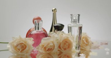 Zarif cam bir yüzey üzerinde zarif güllerle çevrili çeşitli parfüm şişeleri. Lüks ve güzel kokunun özünü yakalar. Zarif Güllü Zarif Parfüm Şişeleri