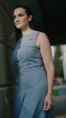 Gün batımında şehir caddesinde yürüyen ve gülümseyen kendine güvenen bir kadın. Modern moda, kadın gücü. Şehirdeki iş kadını. İyi hissediyorum. Ofis binasının yanında kendine güvenen bir iş kadını. Başarı. Kariyer