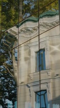 Modern cam bina eski, klasik bir binayı ve ağaçları yansıtır. Yansıma, geleneksel mimariye çarpık bir bakış açısı yaratıyor. Çağdaş arasındaki karşıtlığı yakalamak