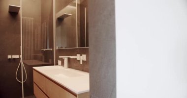 Basitlik tasarımı olan modern banyo. Lüks Banyo İçi, kahverengi renkli minimalist iç mekan, banyo aksesuarları, ayna ve duş başlığı, küvet modern tasarım. Lüks konforlu daire.