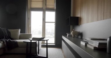 Ahşap duvarlı ve gri mobilyalı modern Minimalist oturma odası. Lüks Modern Ev Köşesi Kanepesi ve Kitaplık. Moda mobilyalar. Rafları ve kitabı olan rahat Modern Mobilya Tasarımı