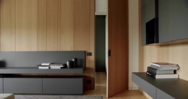 Modern Minimalist oturma odası, ahşap duvarı ve gri mobilyası var. Modern rafları ve kitabı olan minimalist bir ev. Samimi Modern Mobilya Tasarımı. Ahşap kapılı lüks şık bir oda.