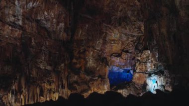 Portekiz 'deki engin ve renkli mağara oluşumlarını keşfeden bir insan, yeraltı manzarasının doğal dokusunu ve güzelliğini geliştiren çarpıcı ışıklandırmayla aydınlatılır..