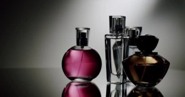 Yansıtıcı bir yüzeyde zarif bir şekilde sergilenen çeşitli parfüm şişeleri tasarımlarını ve renklerini gözler önüne seriyor. Lüks, parfüm ve güzelliğin mükemmel bir temsili. Zarif parfüm şişeleri