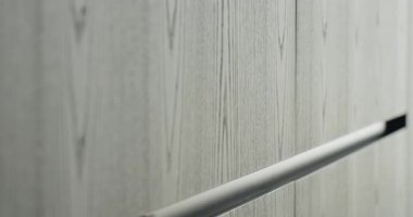 Detaylı çekim, ahşap bir kapının üzerinde paslanmaz çelik bir kol gösteriyor. Minimalist ve modern tasarım odaklı. Ahşap kapıdaki paslanmaz çelik sapın yakın çekim görüntüsü