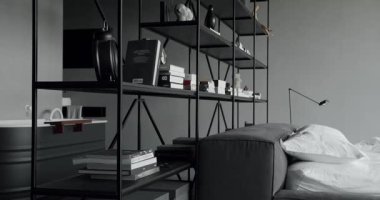 Siyah ve beyaz renkli zarif iç tasarım. Modern yatak odası içi ve bir sürü yastıklı yatak odası. Minimalist İskandinav tarzı iç mekan. Duvarında kitap rafı olan bir yer. Gayrimenkul.