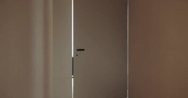 Gösterişli ve modern bir iç tasarım, minimalist bir kapı hafifçe aralık bırakarak, ışığın temiz çizgilerini göstermesine olanak sağlıyor. Minimalist Kapı ve Temiz Çizgilerle Modern İç Tasarım