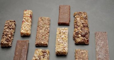 Assorted nutritious granola and protein bars on a gray surface. Ideal for healthy snacks, fitness, and energy boosts. Includes various flavors and ingredients for diverse tastes. Snack Bars