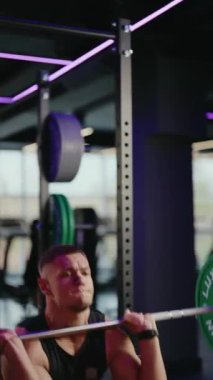 Kararlı bir erkek halterci, güçlü ve formda bir halter egzersizi yapar. Yoğunlukla kaldırıyor, modern, enerjik bir spor salonunda baskı altında kasları geriliyor..