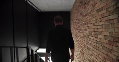 The man descends the stairs in the house from the second floor in the house, Modern interior of loft apartment with large sliding window and brick wall, brick wall background with stair.