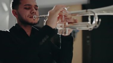 Modern bir stüdyoda trompet çalan bir erkek caz şarkıcısı. Canlı caz konseri. Müzik tutkusu. Genç trompetçinin yakın eli. Müzik odası.