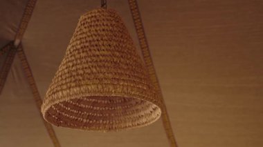 Fas 'ta bir çadırın tavanından sarkan hasır bir abajur. Işık sıcak bir parıltı yayar, sıcak bir atmosfer yaratır. Seyahat, kültür ve iç tasarımla ilgili projeler için ideal