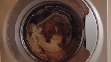 Çamaşır makinesinde dönen giysiler büyüleyici bir kumaş ve su girdabı yaratır. Ritmik hareket ve sabunlu su bir temizlik ve tazelik hissi yaratır. Çamaşırlar, ev işleri.,