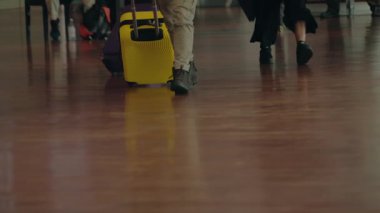 Bagajlı yolcular havaalanı terminalinden geçiyor. İnsanlar bavullarıyla havaalanından geçiyor. Gezginler çantalarını kontrol ettikten sonra kapılarına doğru yürür..