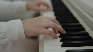 Sessiz bir kişi dairesinde otururken piyano çalışır. Ev müziği stüdyosu kadını. Müzik eğitimi. Eller piyano tuşlarına basıyor. Nota okuyorum. Piyano öğrenme dersleri