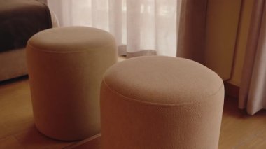 Doğal ışıklandırılmış bir yatak odasında iki boş silindirik bej sedir. İç ayrıntılar ambiyansı güçlendirir. Yaşam tarzı, mobilya, ev dekorasyonu, emlak, otel, Fas, iç tasarım için mükemmel.