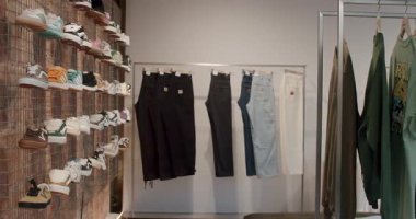 Moda bir pano dükkanında giysi rafları ve raflar şık kıyafetler ve ayakkabılar sergileniyor. Bu kentsel perakende satış yeri son moda sokak kıyafetleri sunuyor. Chisinau, Moldova - 18 Ocak 2025