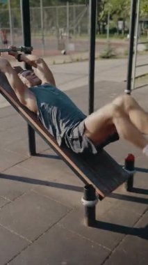 Kararlı bir sporcu, güneşli bir günde güç ve zindelik üzerine eğik bir bankta egzersiz yapar. Görüntü adanmışlığı ve fiziksel bağlılığı yakalar. Odaklanmış Sporcu Egzersizi